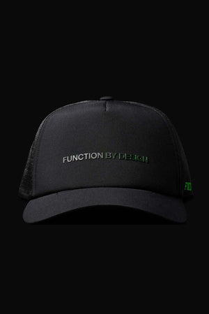 A black FXD CP-13 Trucker Cap with "FUNCTION BY DESIGN" embroidered in gray and green on the front, made from breathable material with an adjustable snap-back, shown against a solid black background.