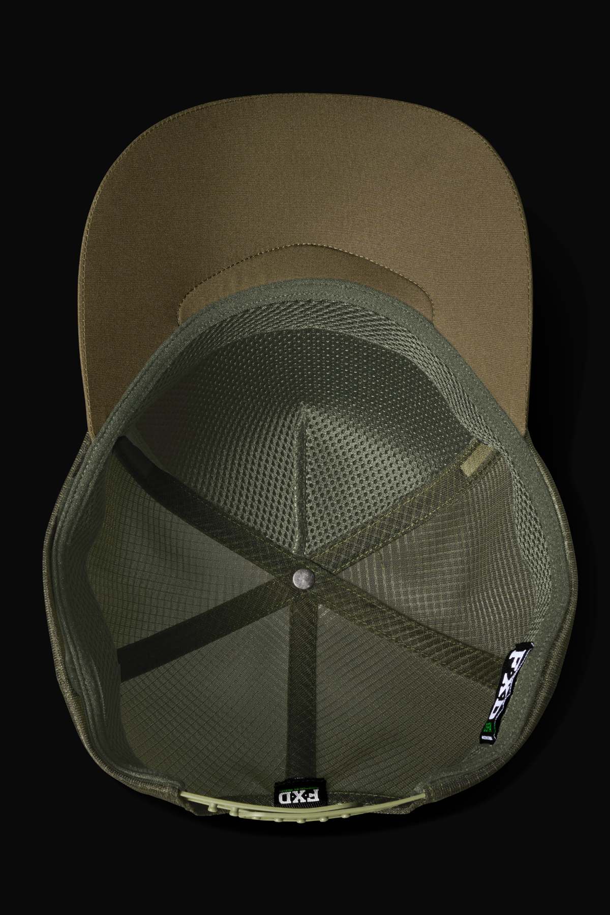 Top view of the FXD CP-13 Trucker Cap in olive green, featuring breathable mesh interior, structured panels, a black and white tag, and a flat brim set against a sleek black background.