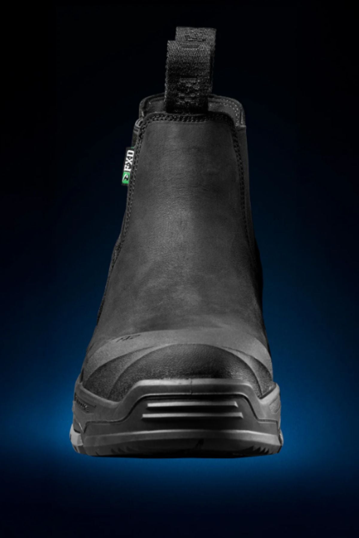 The FXD DURA X-3 Slip On Work Boots, shown in black with a front view against a dark gradient, feature a pull tab, reinforced toe, and advanced NITROCORE sole system for enhanced performance.
