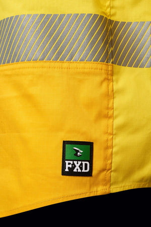 A close-up of the FXD LSH-2T Stretch Taped Hi Vis Long Sleeve Work Shirt with reflective tape. The bottom part of the yellow safety jacket displays a green and black patch with the letters "FXD LSH-2T Stretch" and a small bird logo.