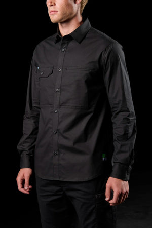 A man stands against a black background wearing the FXD LSH-3 Vented Work Shirt in black. Made from lightweight stretch fabric with chest pockets, the long-sleeve shirt offers comfort and ease. His face is partially visible, hands relaxed at his sides.