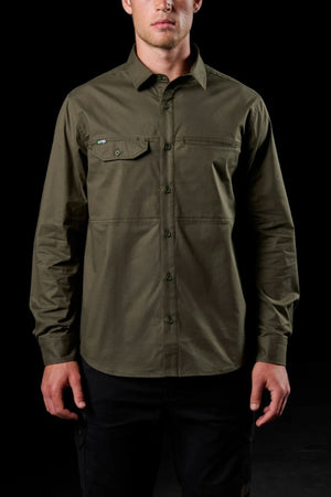 A person in an olive green FXD LSH-3 Vented Work Shirt, featuring long sleeves, a single chest pocket, and lightweight stretch fabric, stands against a black background with their head partially out of frame.