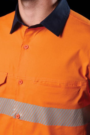 A close-up shows a person wearing the FXD LSH-4T Work Shirt in orange with reflective silver stripes, a dark collar, button front, and chest pockets. Only the lower face and upper torso are visible.