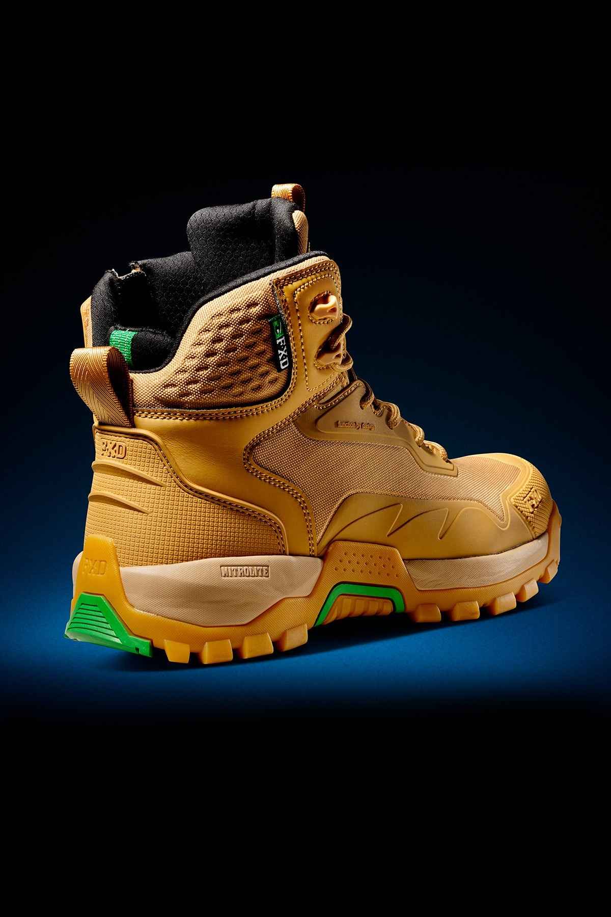 The FXD WB-6 Work Boot is a robust, tan hiking boot equipped with a padded ankle collar, black laces, and a green outsole. It features textured detailing and includes a Poron heel insert for added comfort. The boot also has a convenient loop at the back for easy wearing and showcases a label on the side adorned with green accents. Displayed against a dark gradient background, the FXD WB-6 Work Boot combines style and functionality seamlessly.