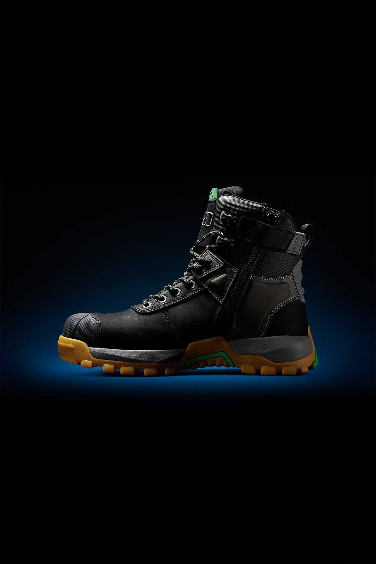 The FXD WB-1 Work Boot in black, featuring a high ankle with green accents and a thick, rugged yellow sole. This boot includes metal eyelets, a side zipper, and reinforced areas for enhanced durability. Additionally, it boasts NITROLITE midsole cushioning for added comfort. The backdrop is black with a subtle blue gradient halo surrounding the boot.