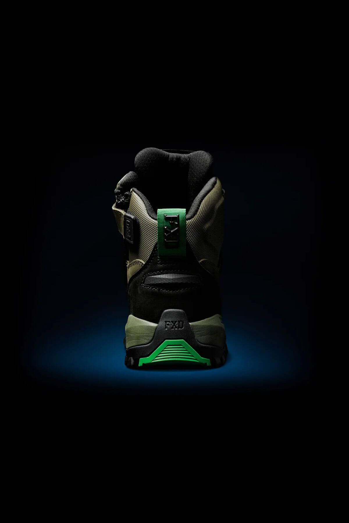 The FXD WB-2 Work Boot is shown from the back, highlighting black and green accents, a side buckle, rugged sole, and NITROLITE midsole cushioning, set against a dark background with a blue spotlight beneath.
