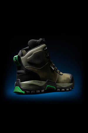 The FXD WB-2 Work Boot in rugged olive green and black with green accents, thick sole, NITROLITE midsole cushioning, and black laces is shown on a dark background featuring a blue gradient glow underneath.