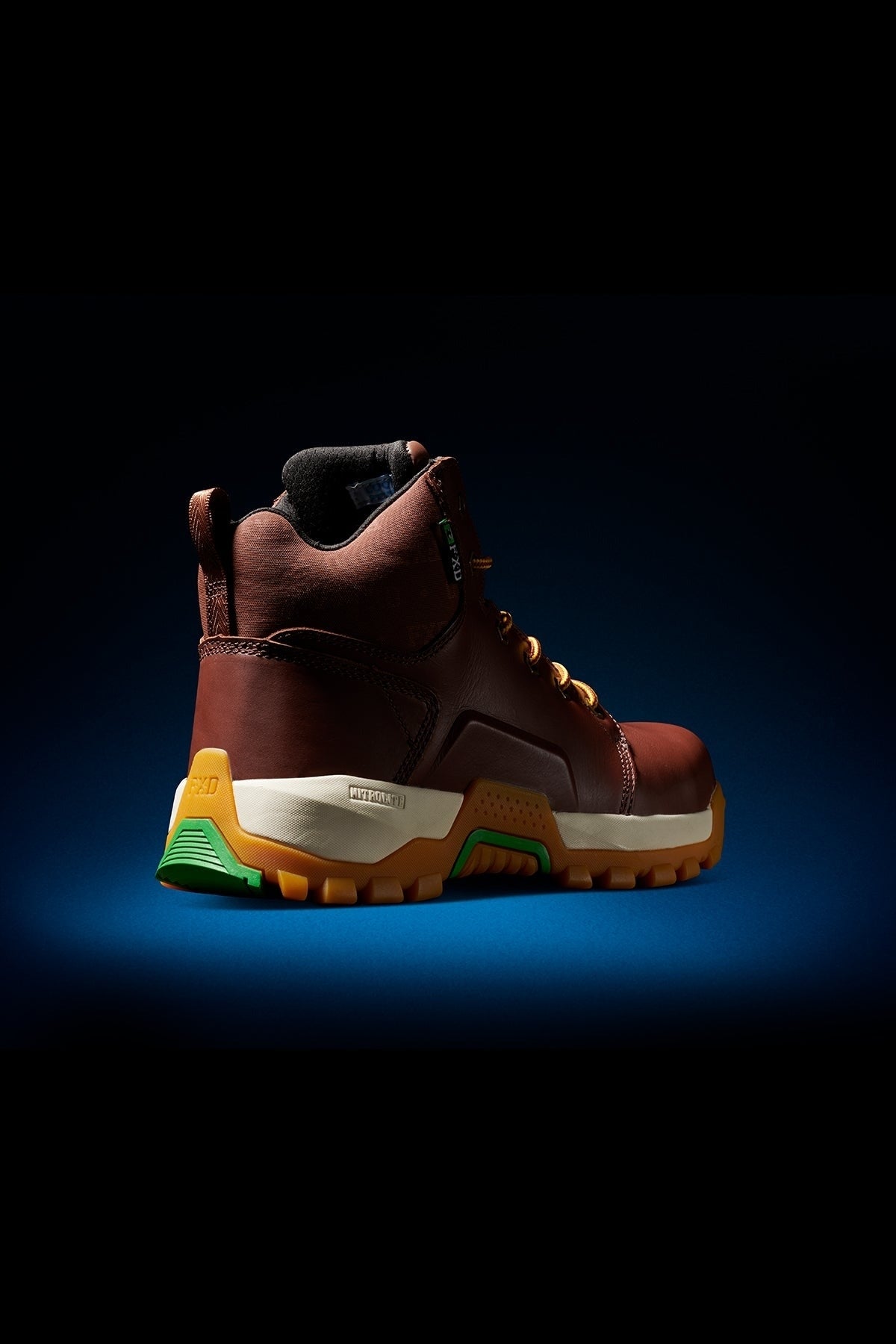 The FXD WB-3 Work Boot features brown premium leather, yellow laces, green and yellow sole accents, a composite safety toe, and a high ankle collar, shown on a dark gradient background.