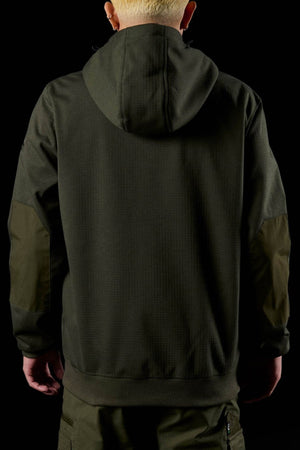 A person with short, light blond hair stands facing away against a black background, wearing a dark green FXD WF-3 Jacket and matching pants.
