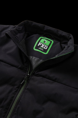 Close-up of the FXD WO-5 Jacket, a black stretch polyester work jacket with a stand collar. The inside label shows "FXD" in bold white with green accents. The partially open zipper reveals the water repellent inner lining.