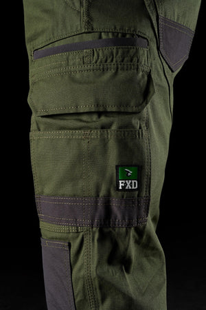 Close-up of a green FXD WP-1 work pant leg showcasing Duratech reinforced pockets and 360-degree stretch for maximum flexibility. The fabric is durable, indicating that the pants are suited for heavy-duty or outdoor activities. The FXD logo is prominently displayed on one of the pockets.