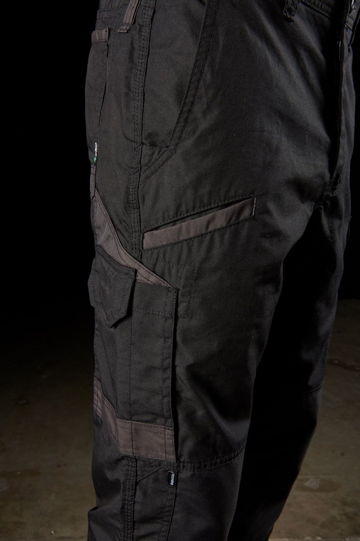 Close-up of a person's lower body wearing black FXD WP-5 pants. The pants feature modern utility pockets and reinforced stitching. The advanced stretch fabric and the dark background emphasize the details and texture of the FXD WP-5 cargo pants.