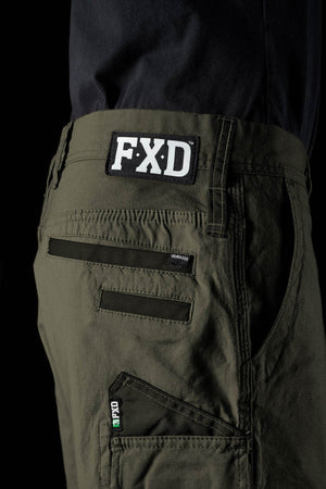 Close-up of a person in olive green FXD WS-3 Short stretch cotton canvas shorts and a black shirt, with the FXD logo patch above the back pocket and detailed stitching highlighting the durable design.