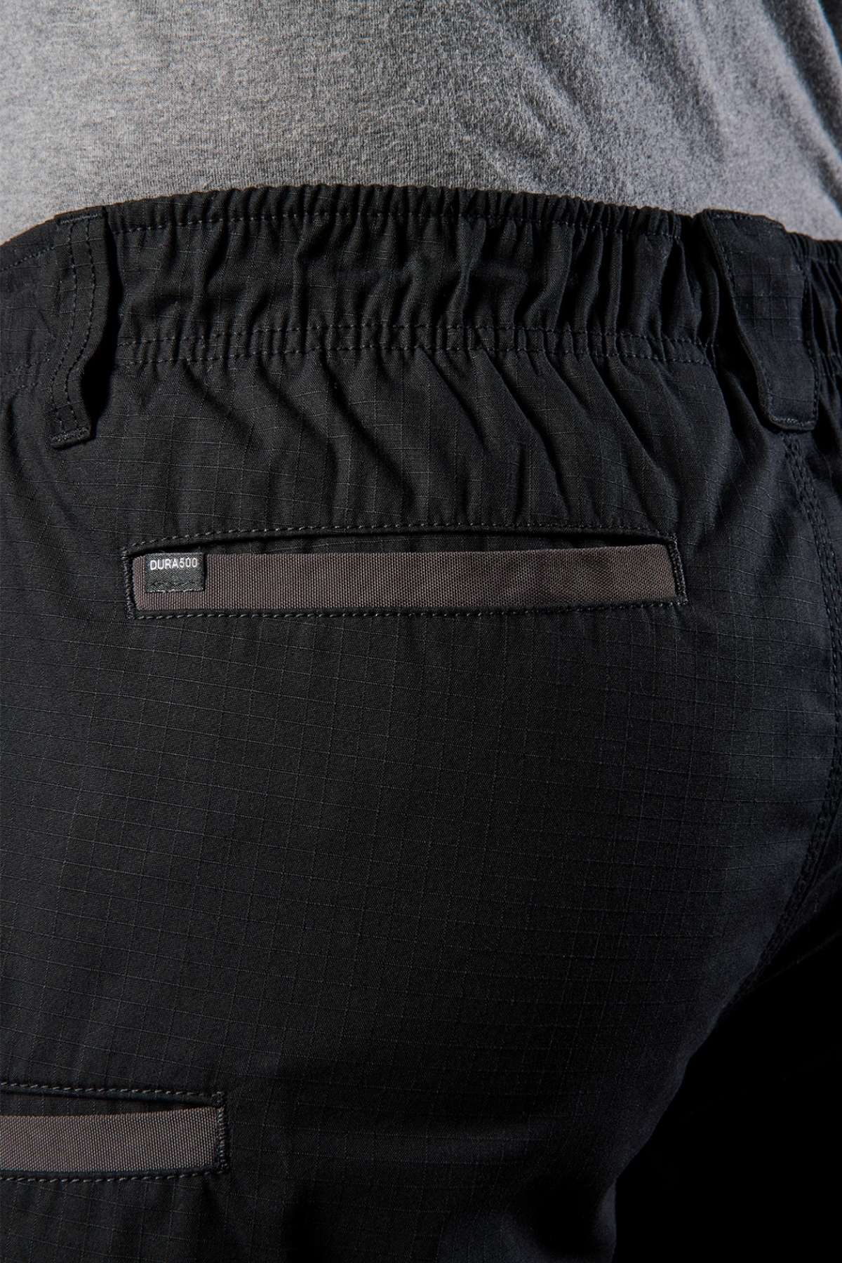 Close-up of the back of a person wearing FXD WS-7 Work Shorts, showcasing their durable design with an elastic waist and a handy pocket. The fabric has a slight texture, and the edge of a gray shirt is visible above.