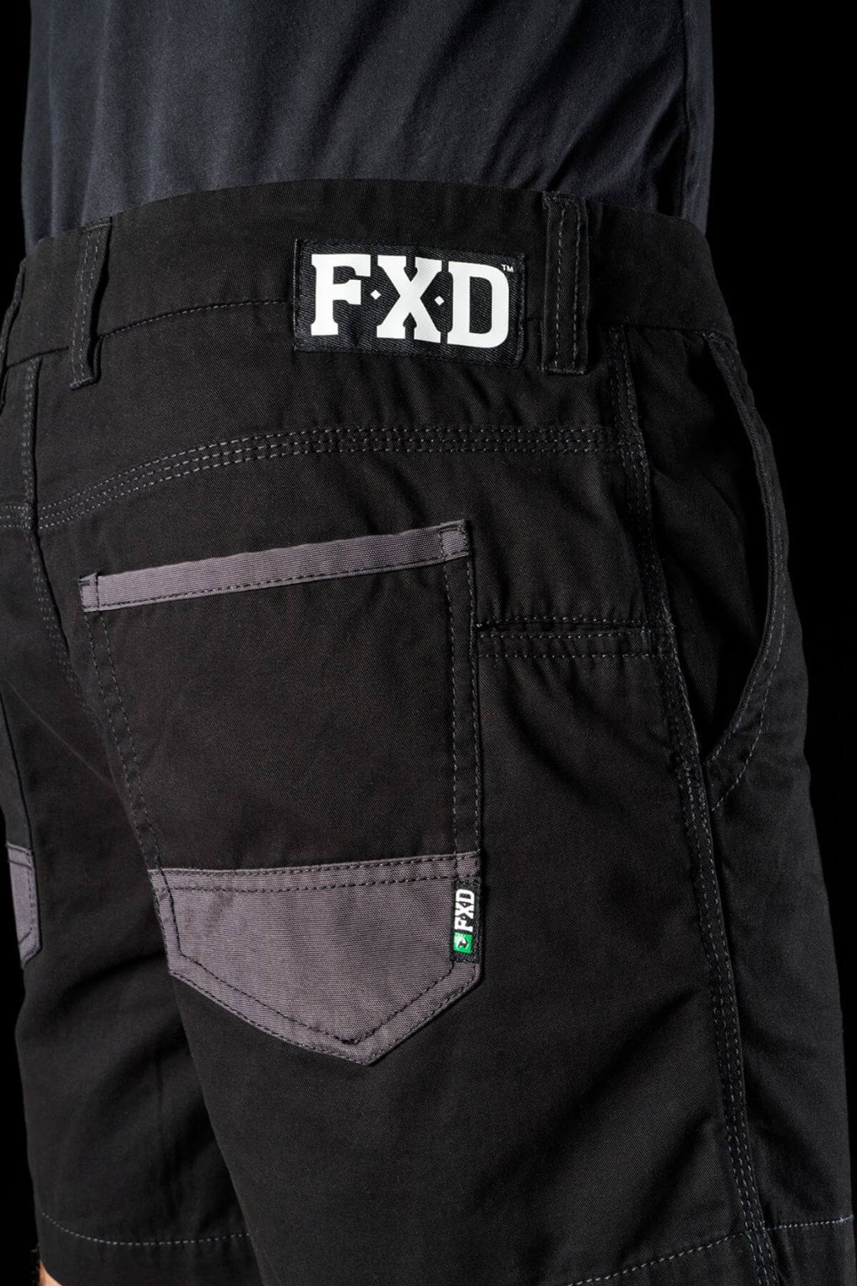 Close-up view of the back pocket of the FXD WS-2 Short Short, showcasing gray accents. These cotton twill shorts feature a visible FXD logo on the waistband and a tag near the pocket flap. With abrasion panels and sturdy construction, they are ideal for heavy-duty tasks.