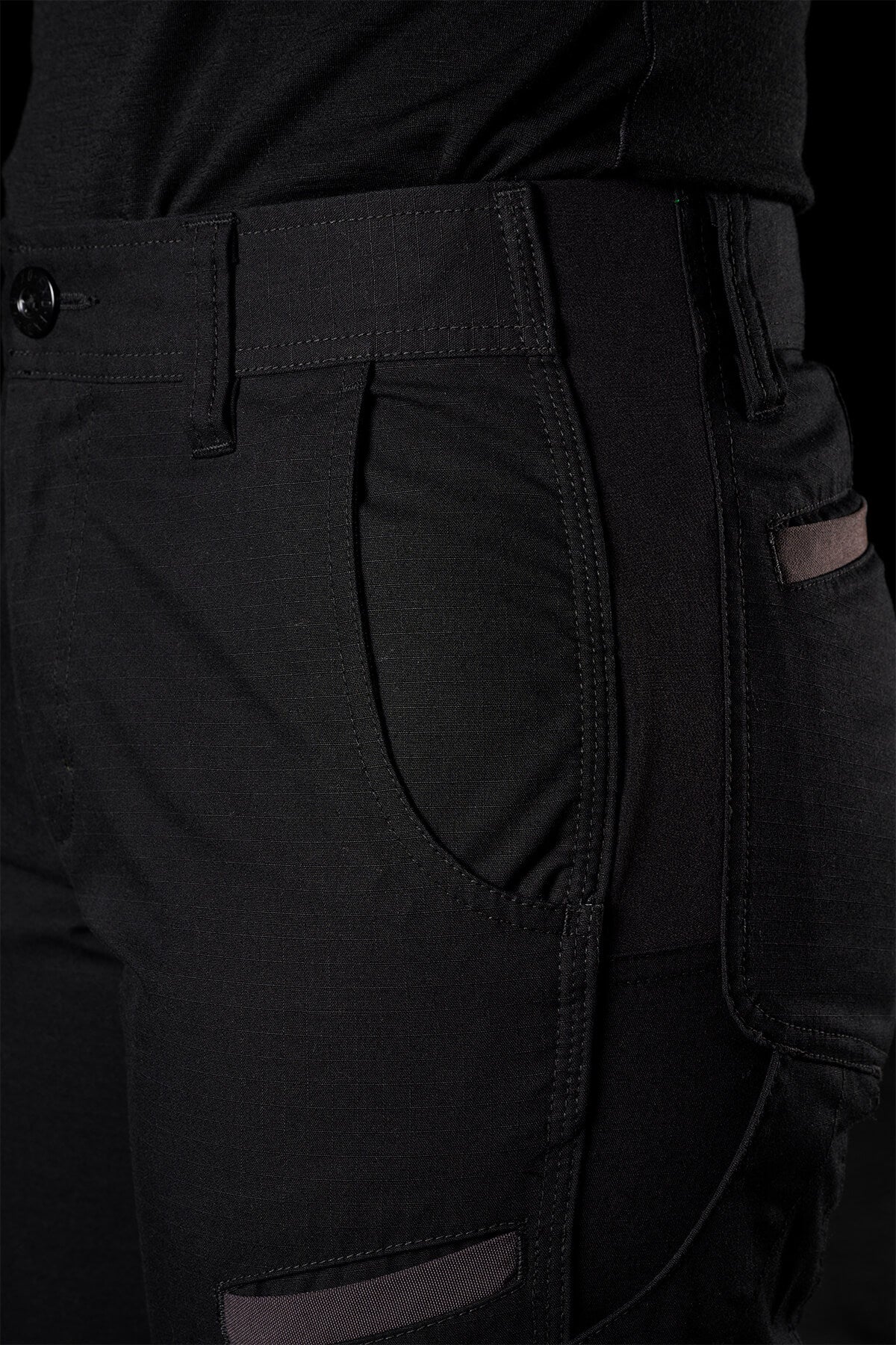 Close-up of a person wearing black FXD Womens WP-8W pants. The image focuses on the side pocket and waistband area, highlighting the precise stitching and fabric texture. The lightweight stretch ripstop material appears to be durable, possibly designed for outdoor or tactical use.
