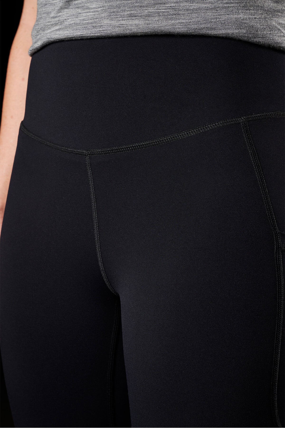 Close-up of a person wearing FXD Womens WP-9W leggings and a gray top. The photo emphasizes the high-rise waistband and midsection of the leggings, which provide 50+ UPF protection.