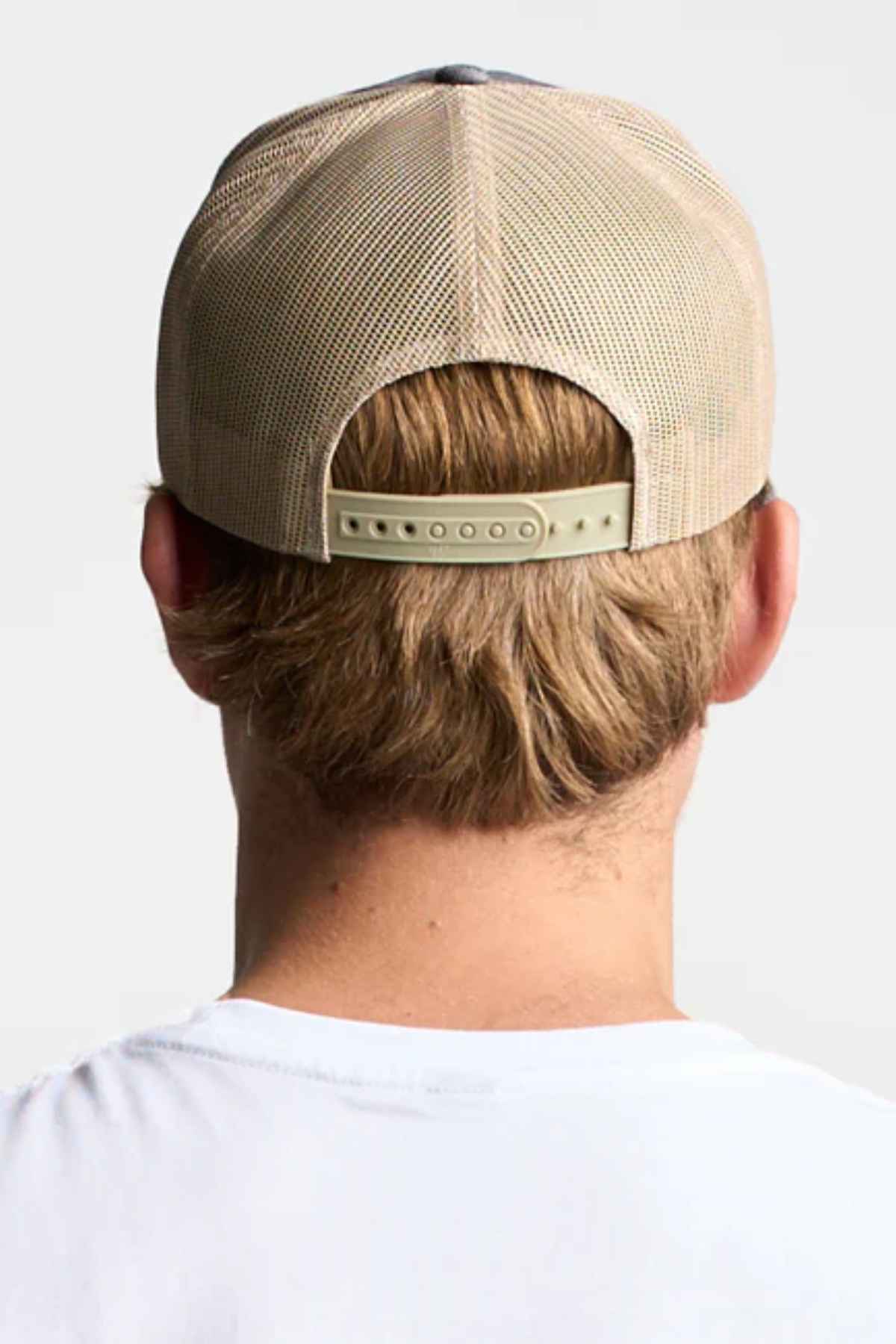 A FlexFit American Stitch Trucker Cap in black and khaki is shown, featuring a mesh back and a snapback strap. The solid black front panel and stitched peak complement the modern headwear label with "Snapback" attached to the brim.