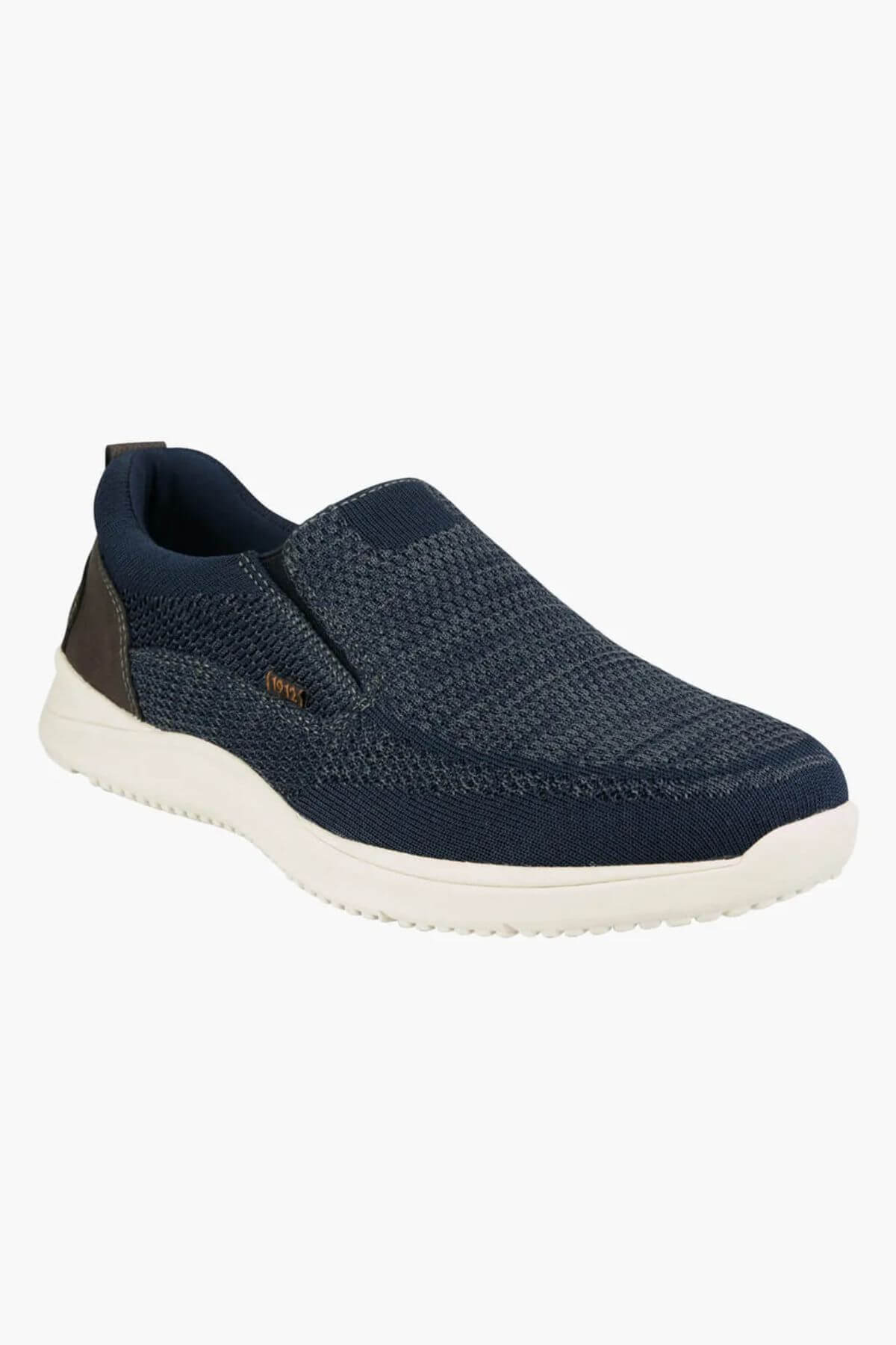 The Florsheim Conway Knit Moc Toe Slip On is a navy blue slip-on sneaker with a textured knit upper, white sole, brown heel accent, and memory foam insole for comfort, shown on a plain white background.