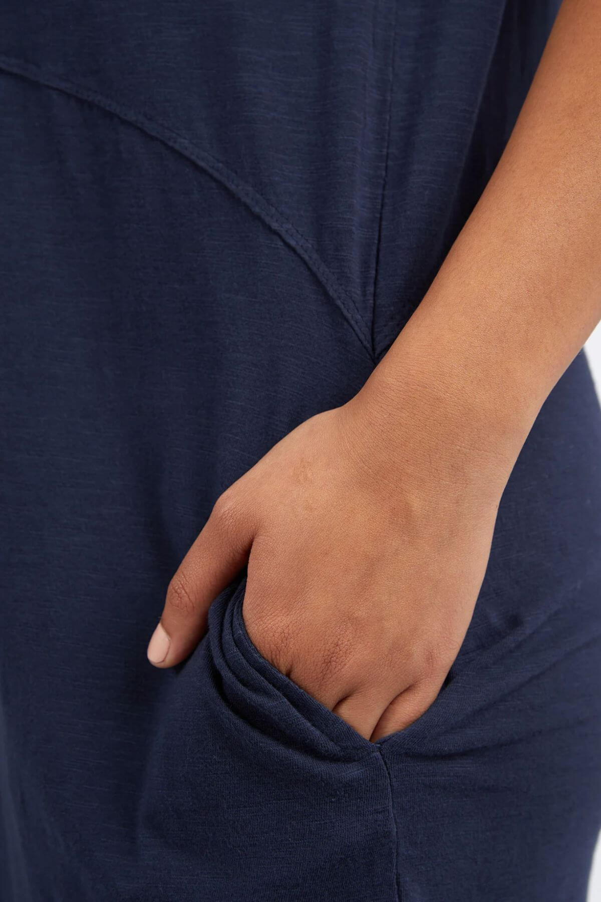 A person casually places their right hand in the side pocket of a Foxwood Bay Dress, a dark blue jersey dress crafted for comfort with soft, inviting fabric.