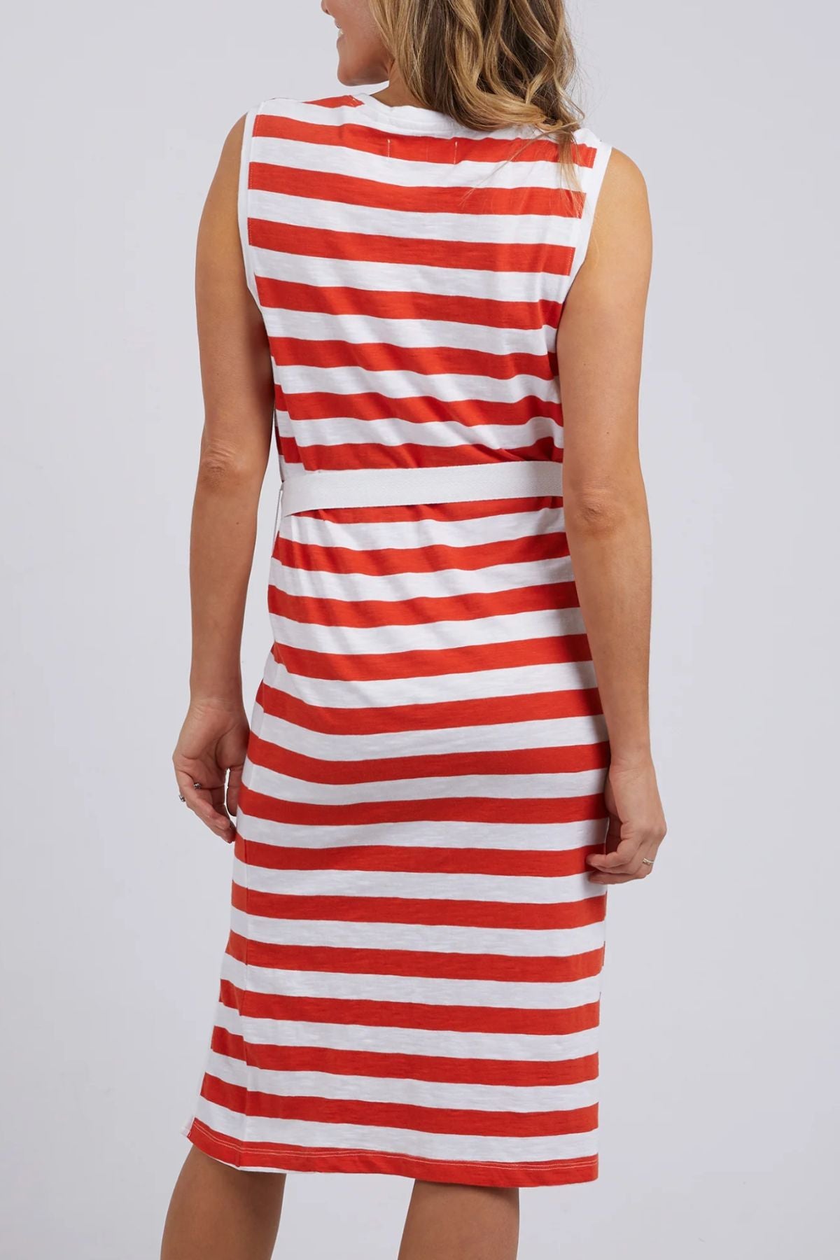 A woman, shown from the back, wears the Foxwood Bondi Stripe Dress—a sleeveless, knee-length dress with horizontal red and white stripes, relaxed fit, flattering cut, and belted waist—against a plain light background.