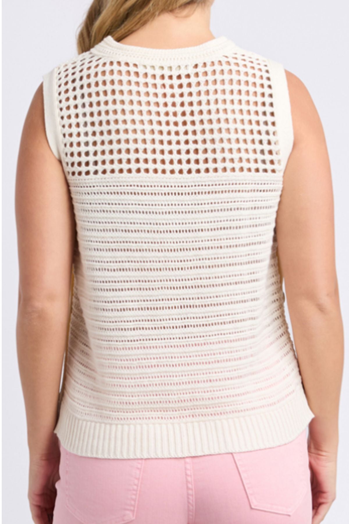 A person is seen from behind wearing a sleeveless, cream Foxwood Chilli Knit Top made of 100% cotton, featuring a patterned semi-transparent back, paired with light pink pants.