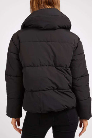 A person is shown from behind wearing the Foxwood Essential Puffer Jacket and black pants. The photo highlights the jacket's quilted texture and thick padding, making it a must-have for any winter wardrobe.