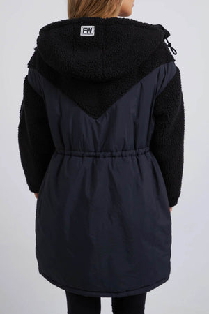 Seen from behind, the Foxwood Longline Anorak features two-tone design with a textured upper and smooth lower section. Ideal for outdoor adventures, this coat is made from durable nylon polyester blend in black, with a drawstring waist and hood adorned by a small logo.