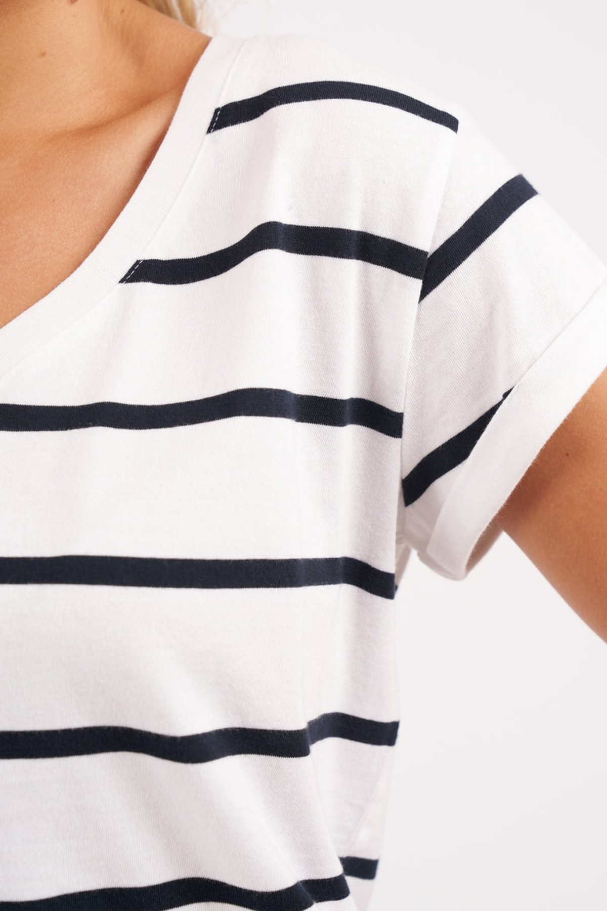 Close-up of a person wearing the Foxwood Manly Stripe Vee Tee, a white T-shirt with yarn-dyed black horizontal stripes. The image highlights the Pima cotton jersey fabric, showcasing its vee neckline and short sleeves that offer comfort and casual elegance.