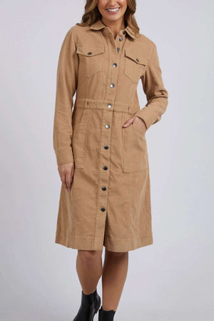 A woman wearing the Foxwood Montana Cord Dress—a knee-length, 100% cotton cord dress with long sleeves and chest pockets—paired with black ankle boots, stands against a plain light background.