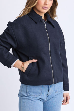 A woman wears the Foxwood Pippa Jacket, a dark navy wool blend with a collar, paired with light blue jeans—an ideal cosy layer for women’s outerwear.