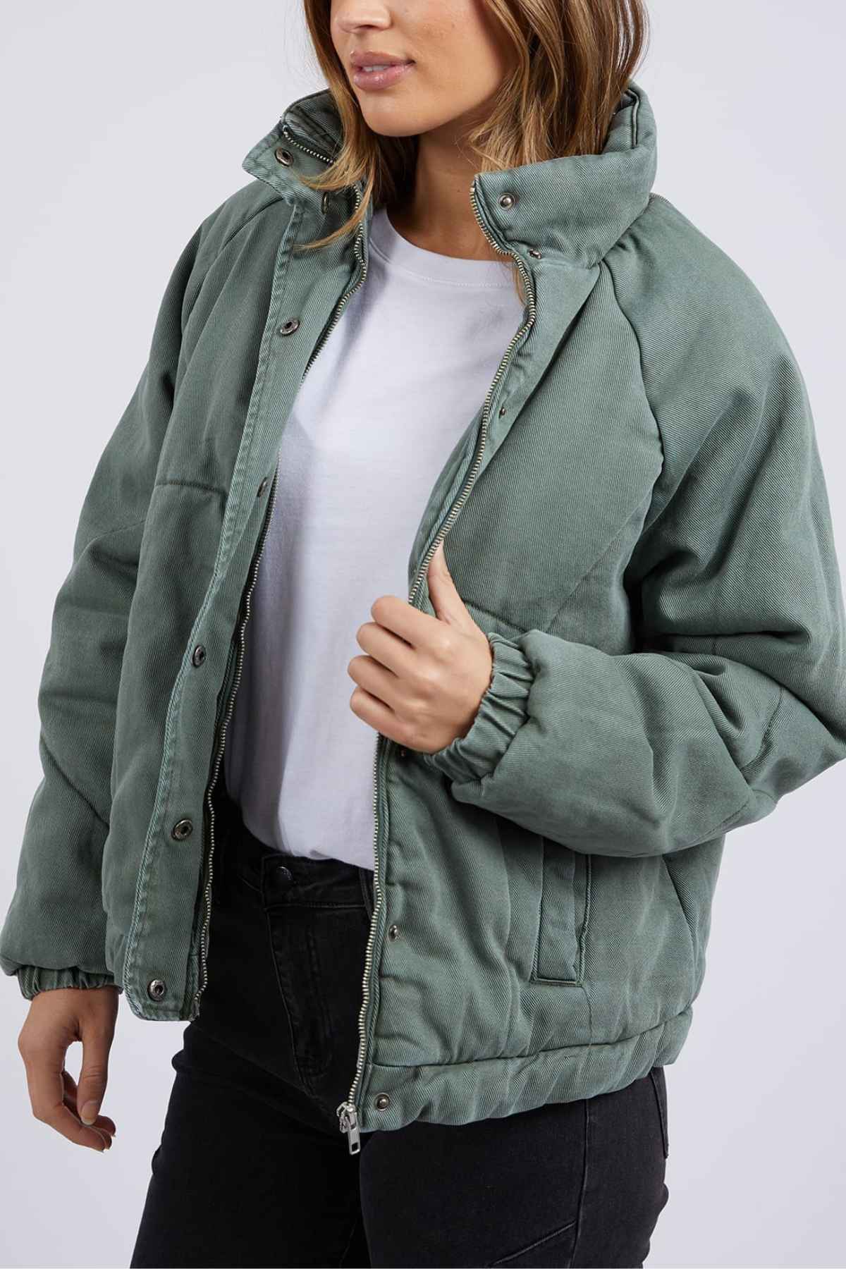 Woman wearing the Foxwood Rosalee Denim Jacket, styled open over a white t-shirt and black jeans, holding the zipper.