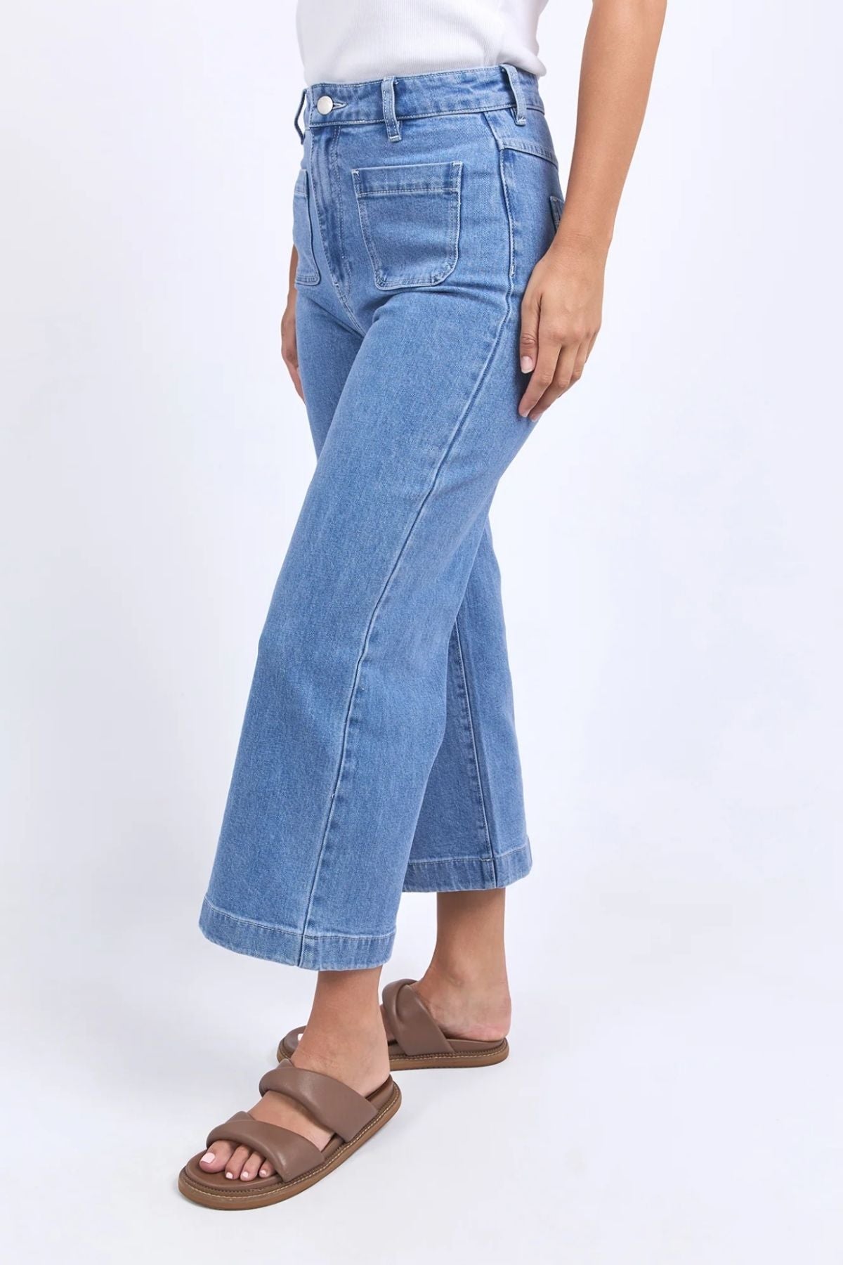 A person wears the Foxwood Sarah Crop Jean in light blue with a white top and brown sandals, standing against a plain white background.