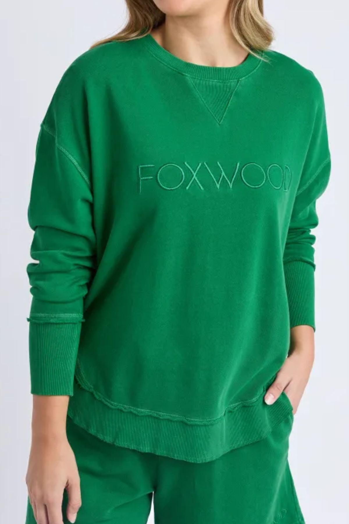 The Foxwood Simplified Crew is a green cotton crew neck sweatshirt with an embroidered logo, ribbed cuffs and hem, and a relaxed fit. Shown paired with matching green pants.