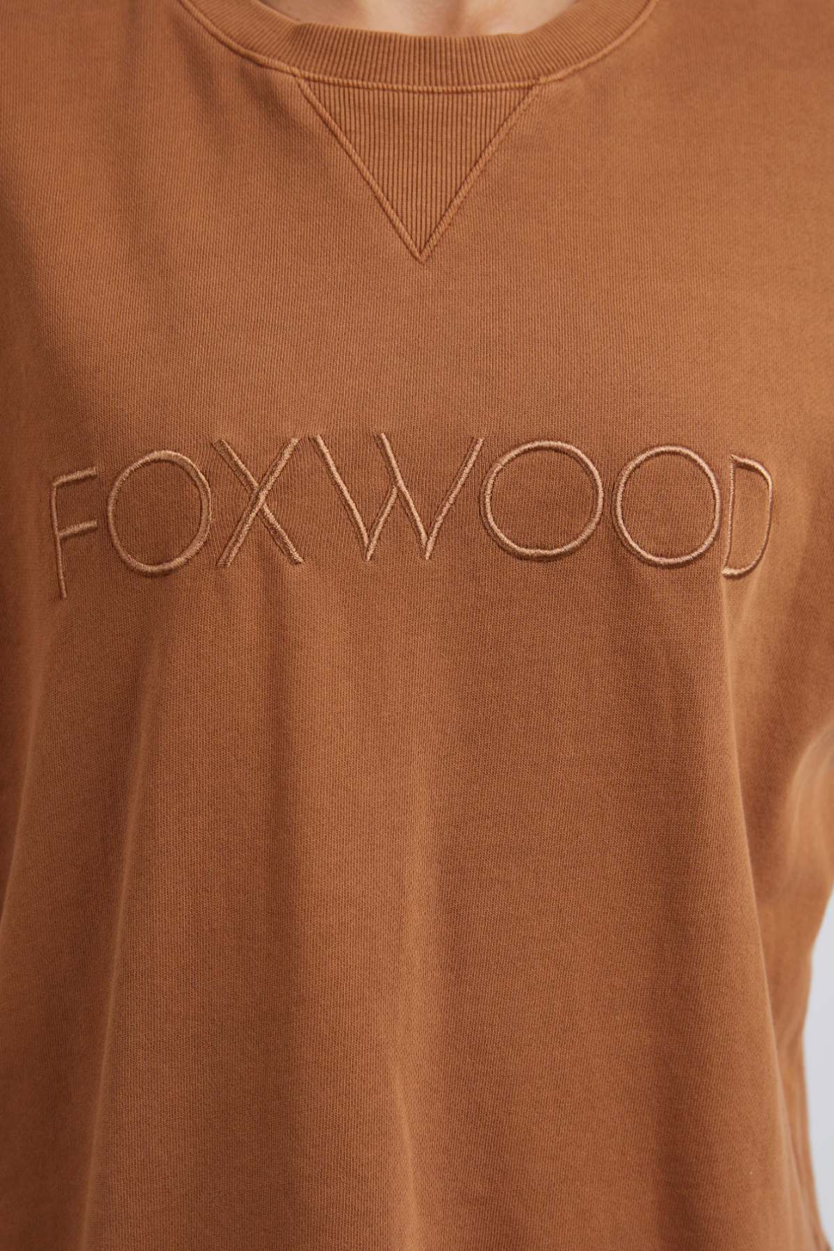 Close-up of the Foxwood Simplified Crew, a brown sweatshirt made from 100% cotton, featuring bold "FOXWOOD" embroidery in large capital letters across the chest.