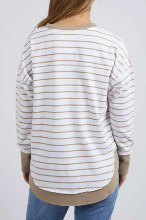 A person with long hair wears the relaxed fit Foxwood Simplified Stripe Crew, made from 100% cotton, with beige cuffs and hem. They're turned away in blue jeans on a light background.