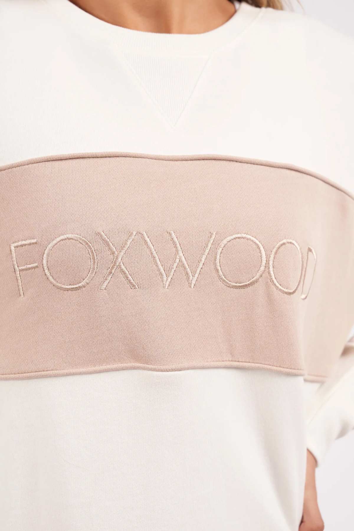 Foxwood Simplified Tonal Crew - Vintage White. Close up image of Foxwood logo embroidery on the front of jumper on model.
