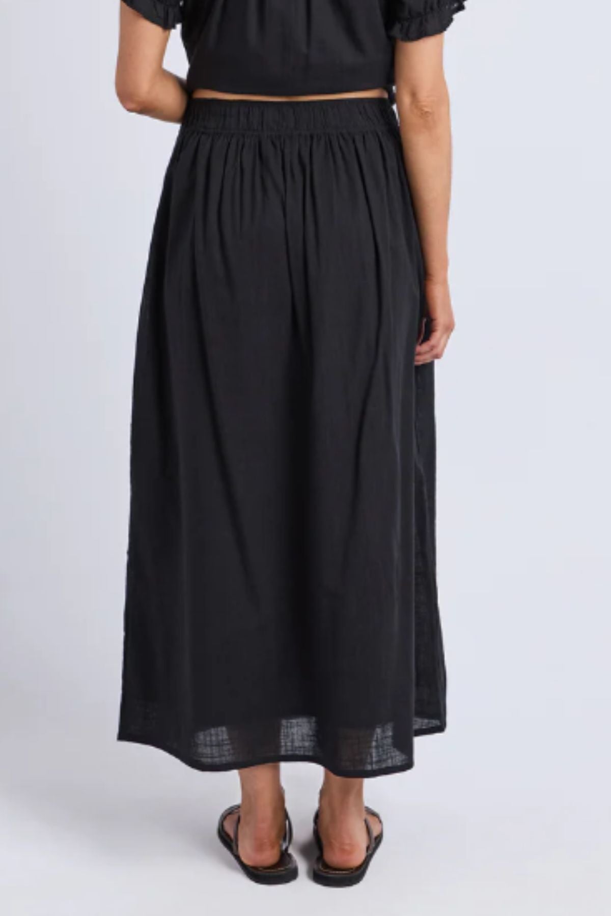 A woman wears the Foxwood Tiana Skirt, a maxi skirt featuring an elastic waistband in classic black.