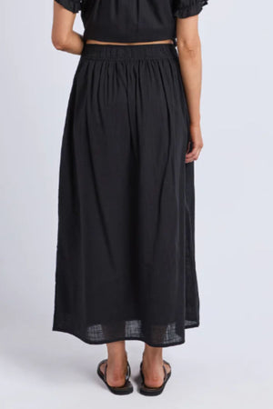 A woman wears the Foxwood Tiana Skirt, a maxi skirt featuring an elastic waistband in classic black.