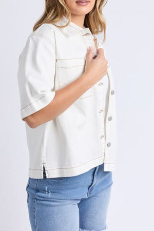 A woman models the Foxwood Valletta Short Sleeve Shirt in white, styled with blue denim shorts. She stands against a plain white background, showing only her torso and upper legs.