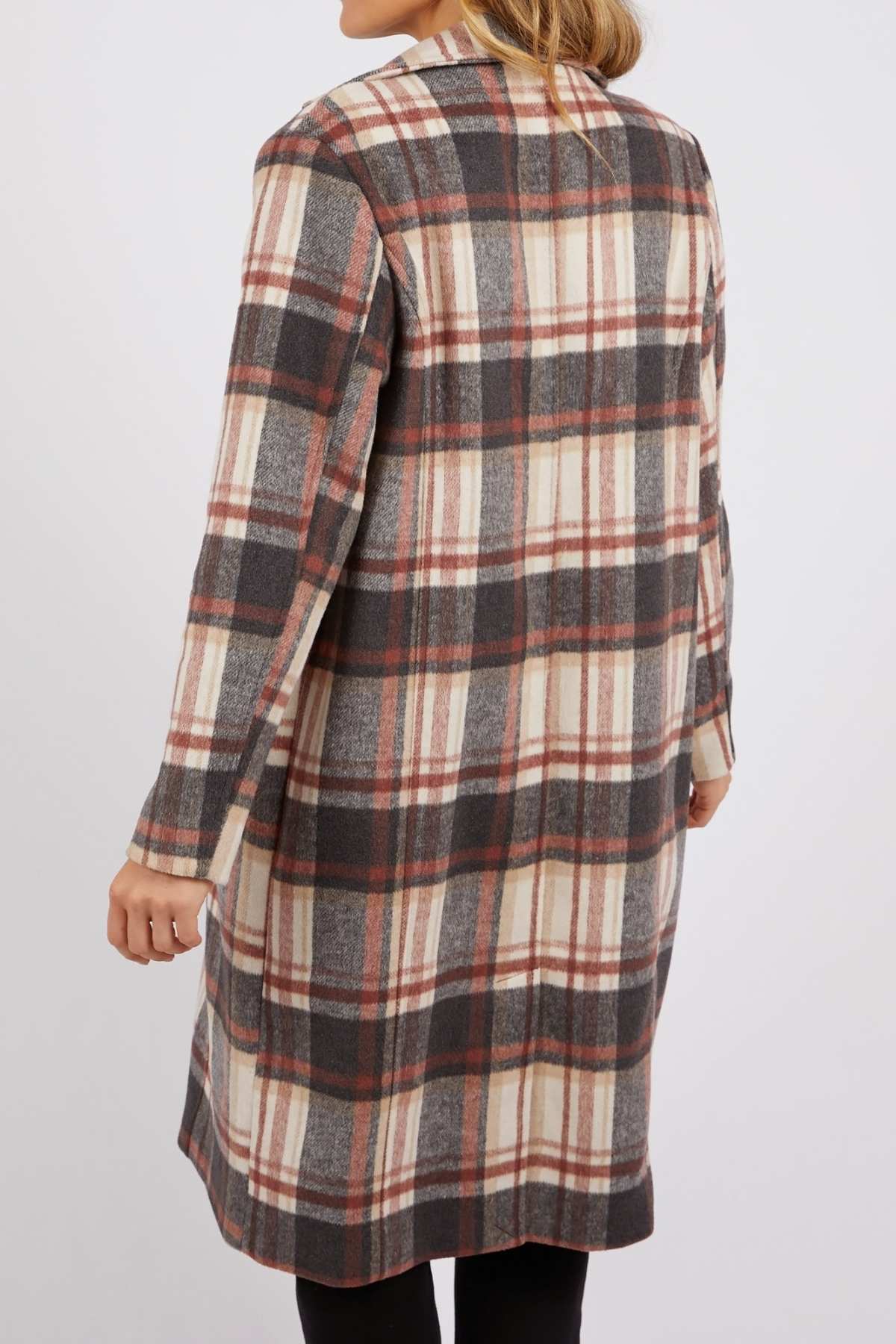 A person stands with their back to the camera, wearing a long Foxwood Westward Coat in cream, gray, and rust check, against a plain white background.