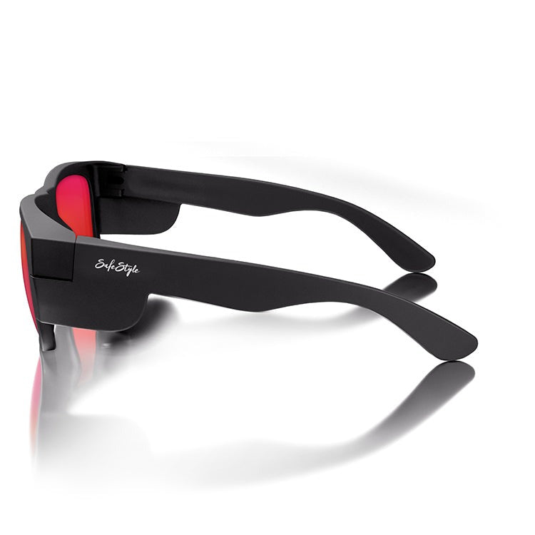 A pair of sleek SafeStyle Fusions sunglasses with a matte black frame, mirror red polarised lenses, displaying the brand "SafeStyle" on the side. Positioned on a reflective surface, these glasses showcase an elegant and modern design while offering UV protection.