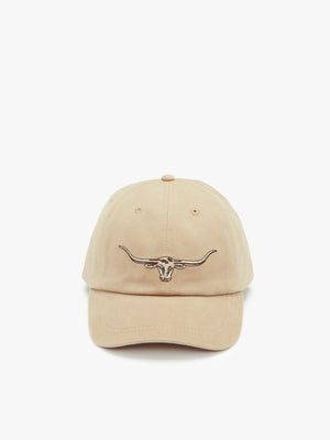 The RM Williams Longhorn Cap is a beige cotton twill baseball cap featuring an embroidered longhorn skull design on the front. It has a curved brim, six panels, and a button on top, all set against a plain light-colored background.