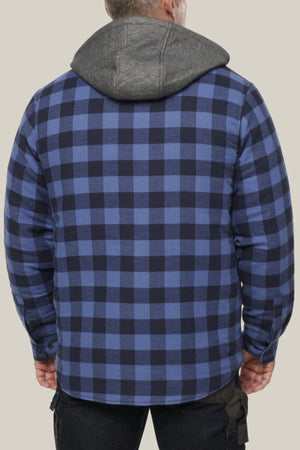 A person is seen from the back wearing a blue and black plaid Hard Yakka Quilted Flannelette Shacket with a gray hood, standing against a plain beige background.