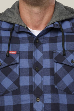 A person wears the Hard Yakka Quilted Flannelette Shacket in blue and navy plaid, featuring black buttons, a gray hood, two chest pockets, and a small red tag on the left pocket.