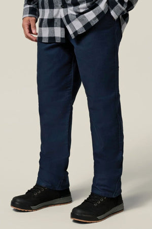 A person in a black and white checkered shirt, dark blue Hard Yakka Moleskin Plain Front Heavy Duty Work Pant, and black shoes stands against a plain light background. The image is cropped at the shoulders to highlight the pants and shoes.