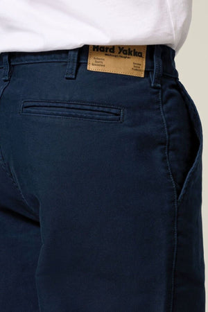 Close-up of a person wearing Hard Yakka Moleskin Plain Front Heavy Duty Work Pant in dark blue, showcasing the brown waistband label and back pocket, paired with a tucked-in white shirt. Focus is on the pant's waist and pocket area.