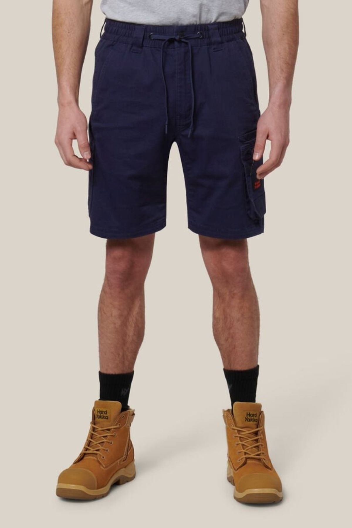 A man wearing Hard Yakka Tough Maxx Mid Short work shorts and brown boots.