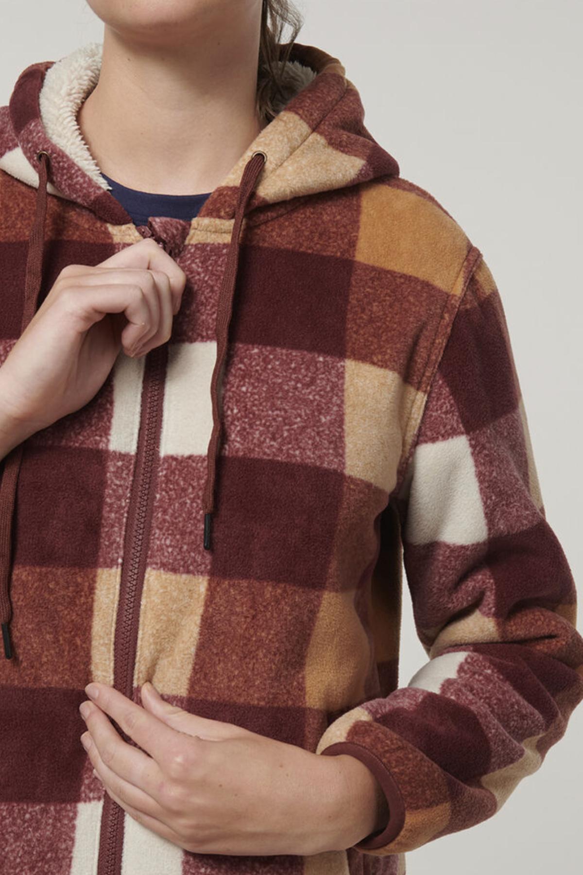 A person is shown from shoulders to hips wearing the Hard Yakka Womens Check Zoodie, a hooded fleece jacket with thermal insulation and a large plaid in maroon, mustard, and cream—one hand pulls the zipper, the other on their stomach.