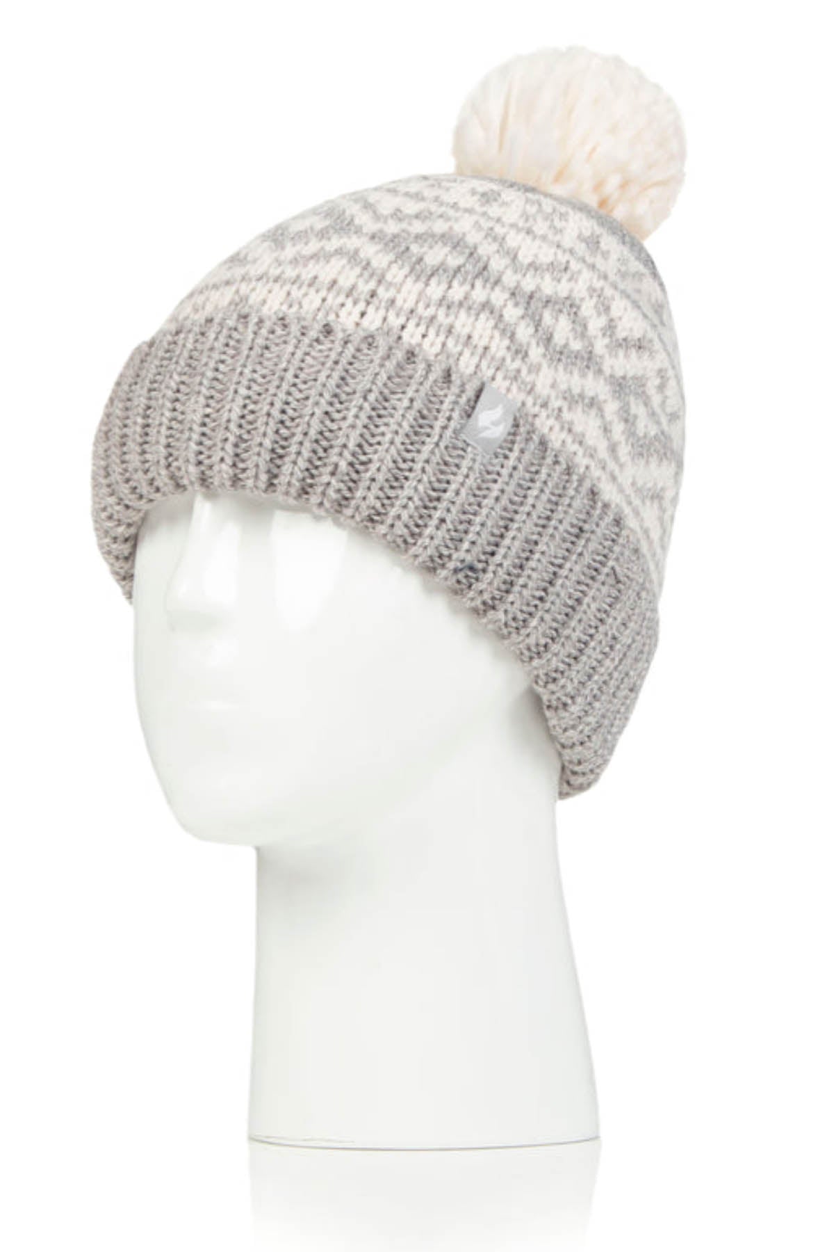 A white mannequin head showcases the Heat Holders Aspen Pom Pom Turn Over Ladies Thermal Beanie, which features a knitted design with a folded, ribbed grey brim and a patterned light grey and cream-colored top. The look is completed with a fluffy cream pom-pom on top.